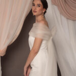 Abito da sposa modello Bustier in duchesse di seta con spacco, bustier dritto e stola in tulle drappeggiato sulle spalle, stile elegante e moderno
