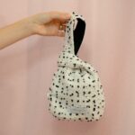 Mini borsa Aki in bouclé bianco e nero con fodera a contrasto nera, forma originale annodata, stile moderno e artigianale