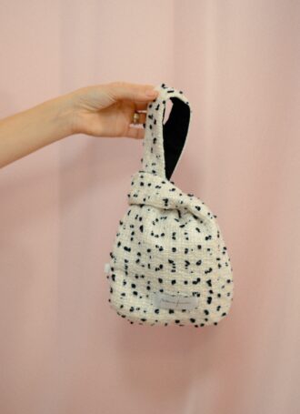 Mini borsa Aki in bouclé bianco e nero con fodera a contrasto nera, forma originale annodata, stile moderno e artigianale